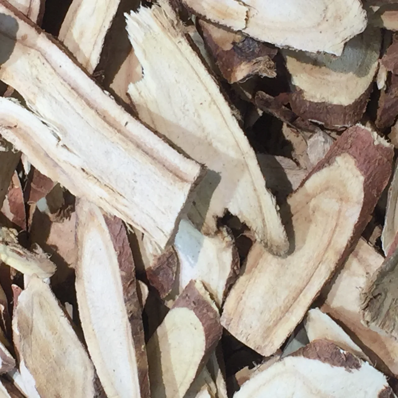 Pale sliced pieces of licorice root with dark brown bark