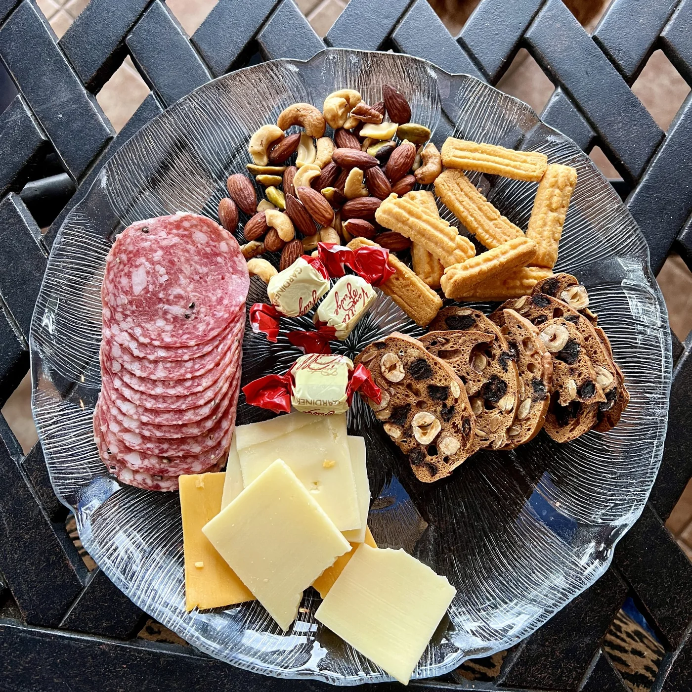 A snack plate with mixed nuts, crackers, cheese, and wrapped candy