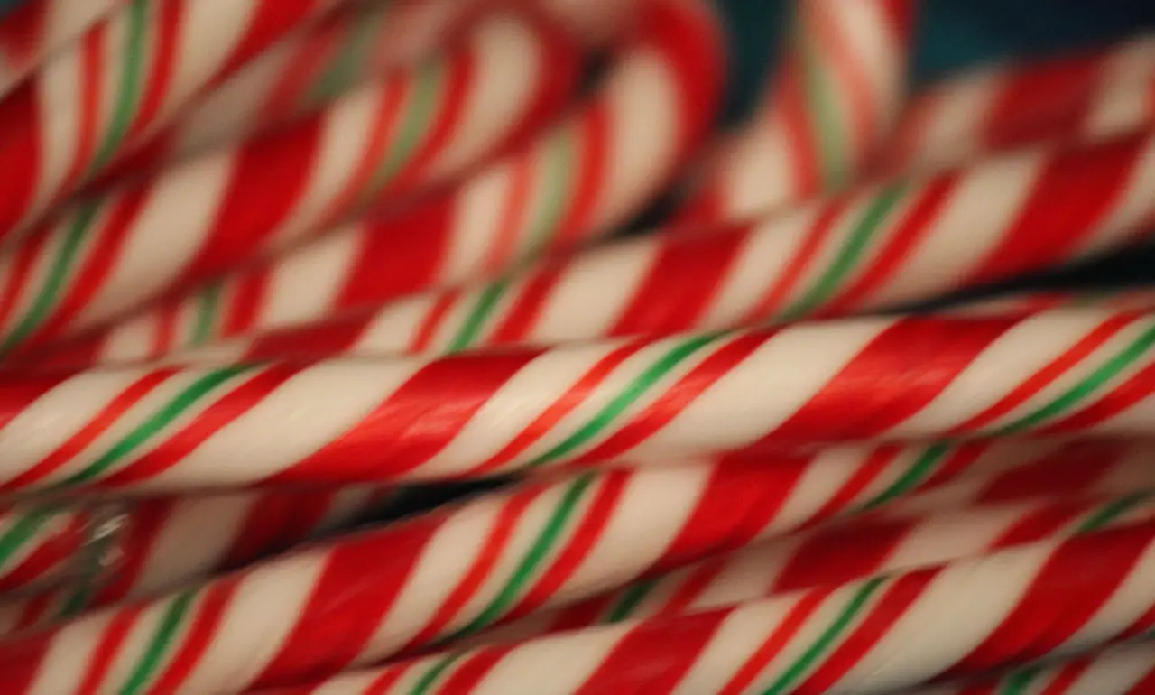 Red, white, and green striped candy canes arranged in a loose overlapping pile