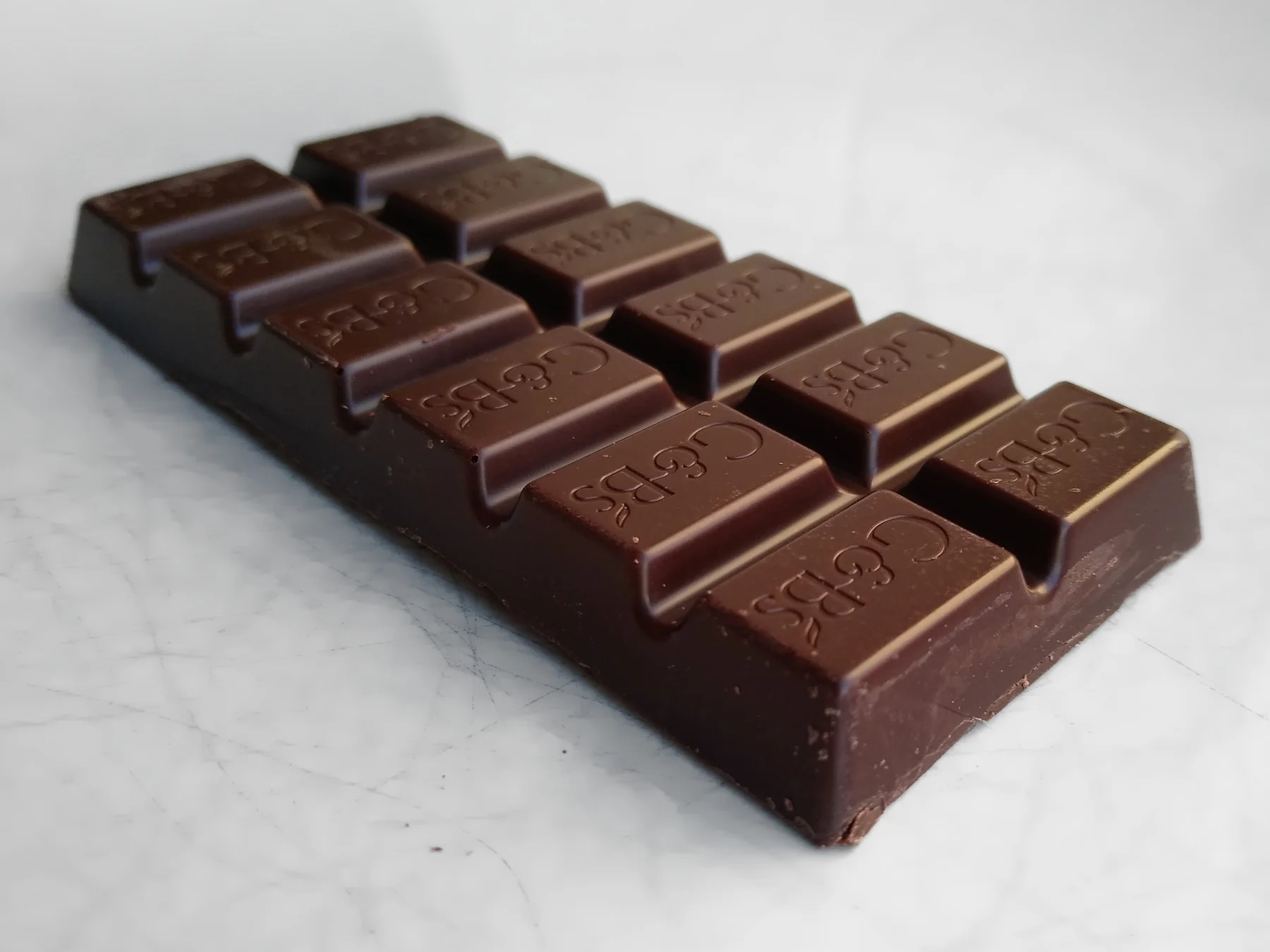 An opened dark chocolate bar resting on a white surface