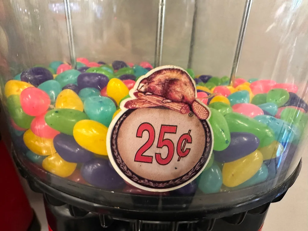 A glass candy jar filled with colorful sweets and a 25-cent sign