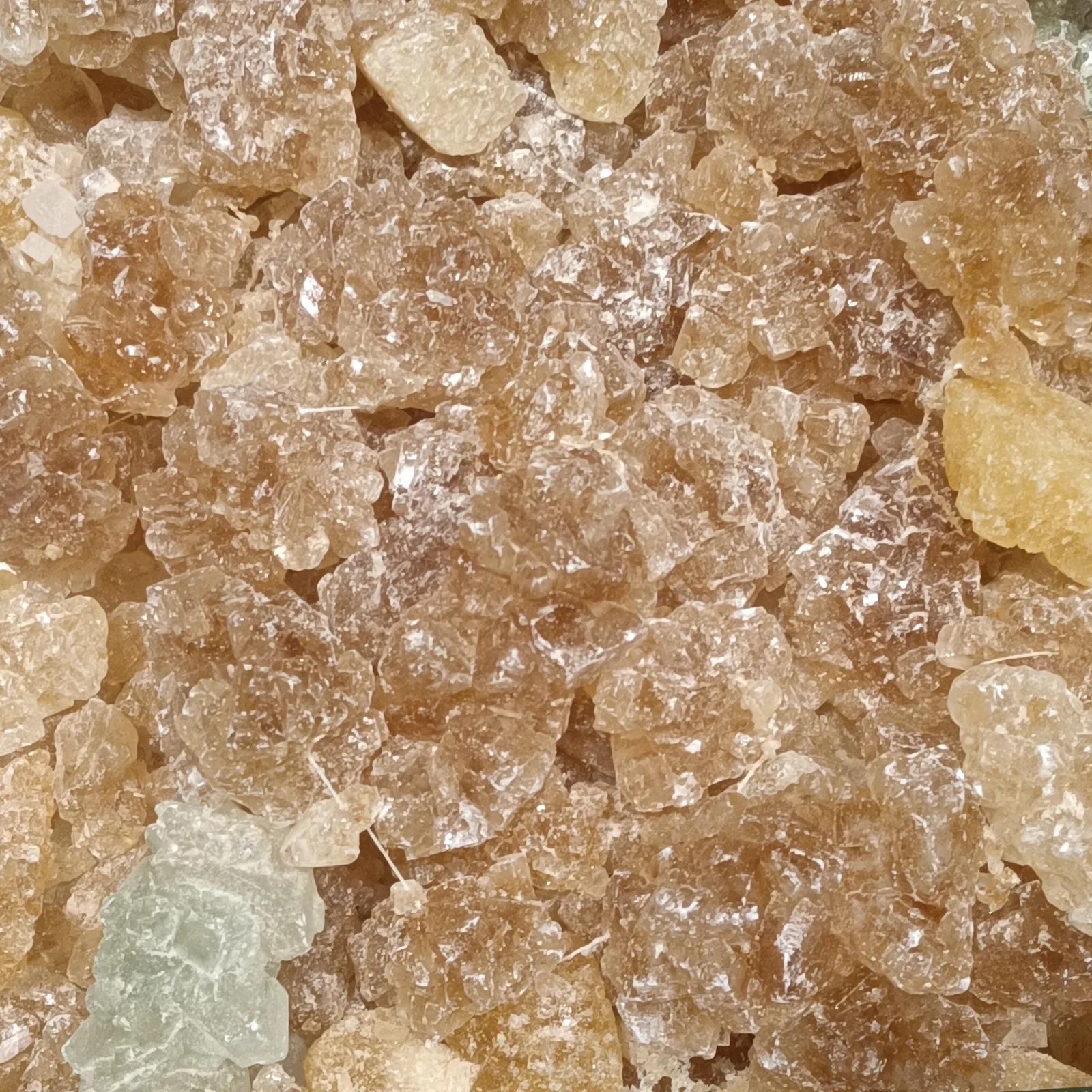 Close-up of amber, pale yellow, clear, and light blue chunks of translucent rock candy