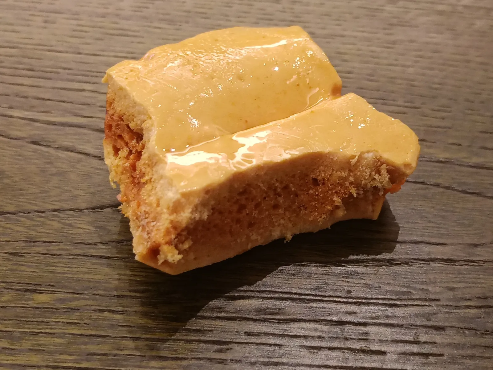 Two golden brown pieces of honeycomb toffee on a dark wooden table